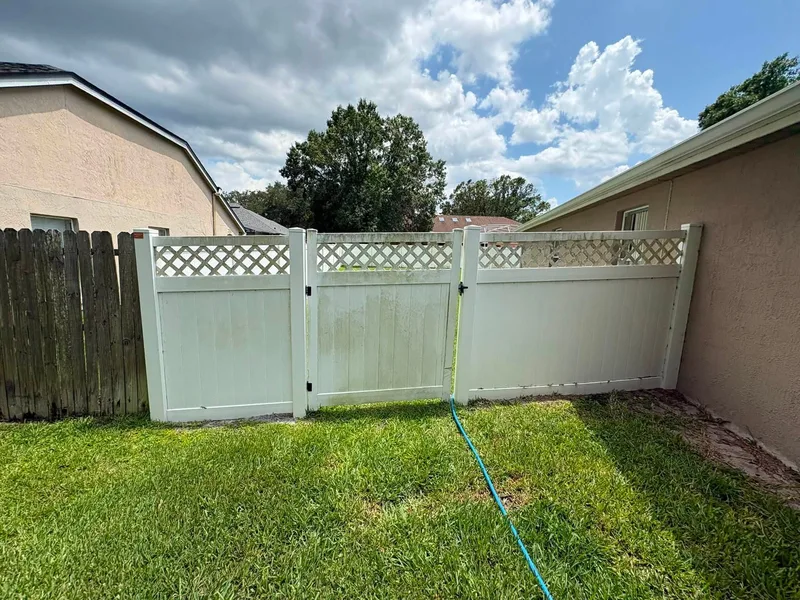 White vinyl lattice-top fence and gate stained with green algae