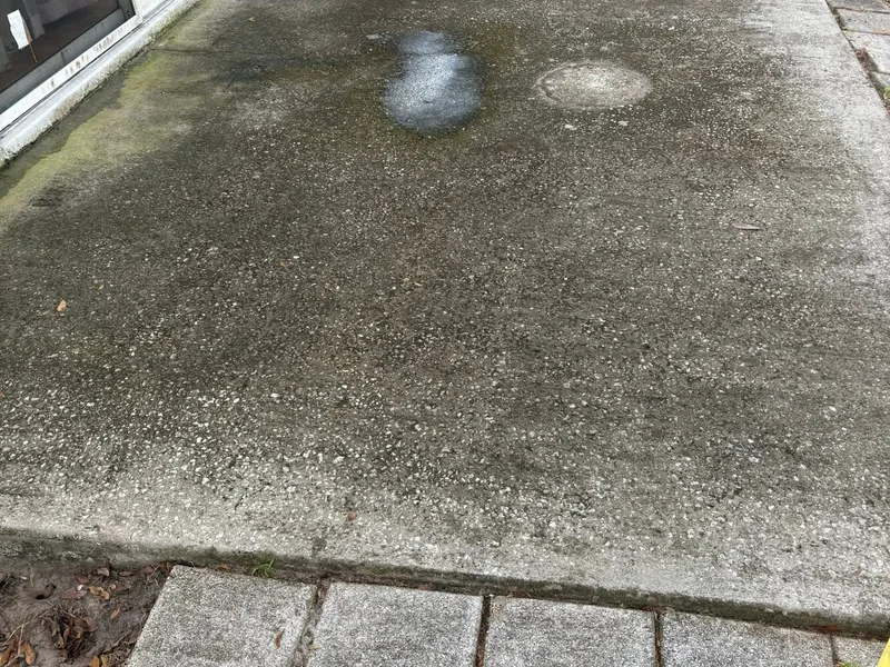 Backyard concrete patio heavily blackened with mildew beside an AC unit