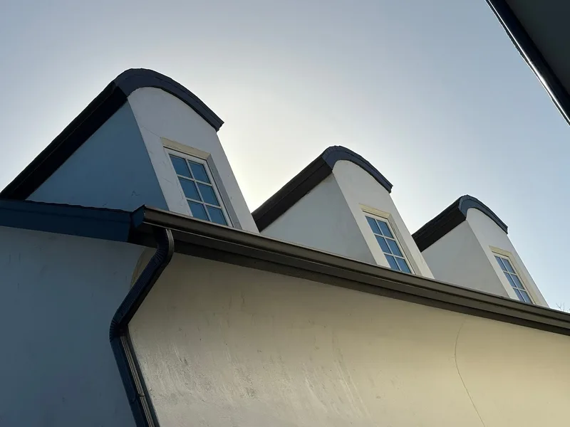 Three clean white stucco dormers against a clear sky after soft washing in Oviedo FL