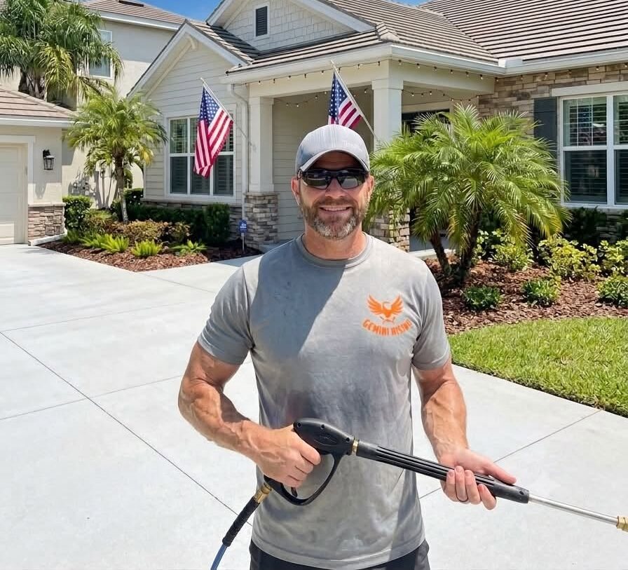 Dan of Gemini Rising Pressure Washing smiling with a pressure washing wand in front of a freshly cleaned Oviedo home